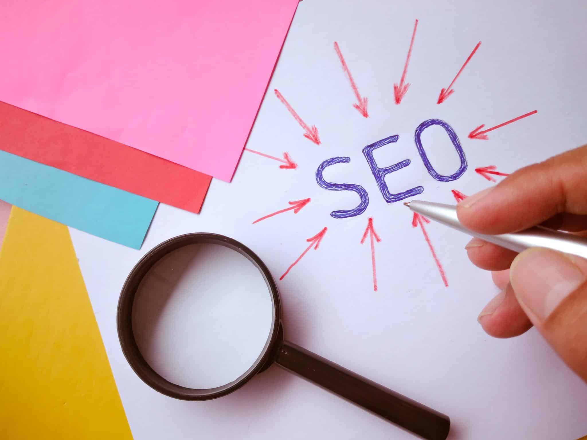 graphic representing SEO, with magnifying glass and colored sheets