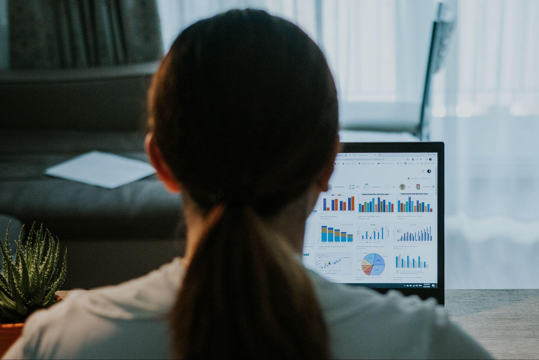 woman working with graphs and charts on a laptop screen
