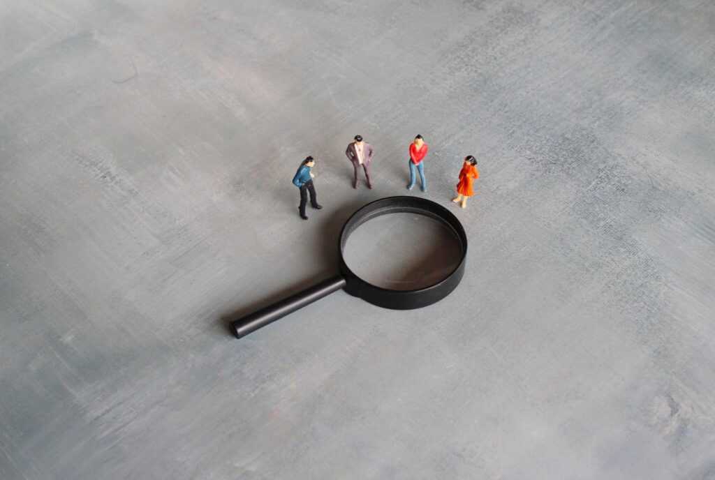concept illustration of search, showing a magnifying glass and a group of miniature figures looking at it
